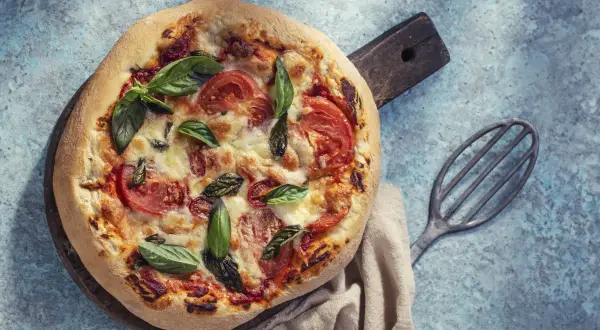 Pyszna pizza na cieście bez drożdży, z pomidorami i bazylią, gotowa do podania.