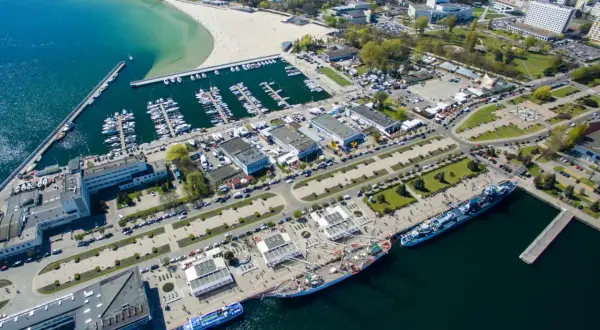 Gdynia co zobaczyć: malownicza plaża, pełny jachtów port, statki i miejska panorama. Idealne miejsce na spacer i podziwianie widoków.