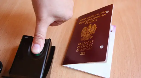 Palec na czytniku linii papilarnych obok polskiego paszportu. To pokazuje, ile ważny jest paszport w podróży.