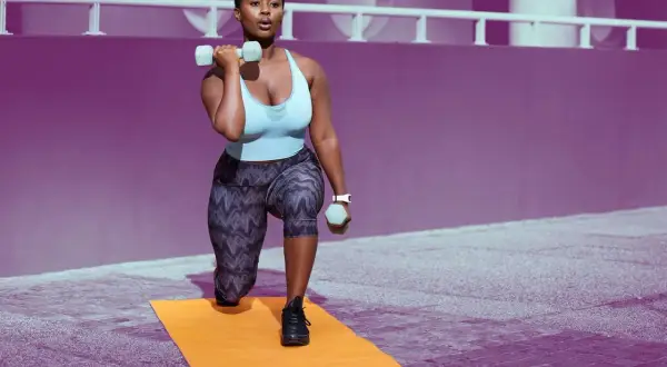 Woman performing lunges with dumbbells, building shoulder endurance exercises.