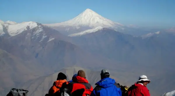 Vier Wanderer blicken auf das majestätische Demavend-Gebirge im Iran.