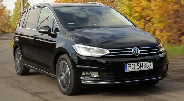 Czarny Volkswagen Touran 1.9 TDI 105 KM szarpie przy przyspieszaniu, jadąc po drodze wśród jesiennych drzew.