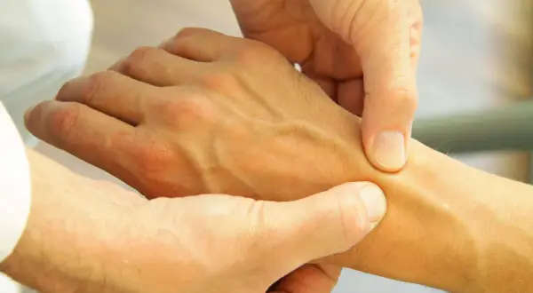Arzt untersucht Hand, um Schmerzen in der Hand zu diagnostizieren.