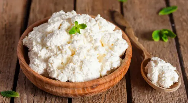 Fiocchi di latte in una ciotola di legno, guarniti con menta. Attenzione, i fiocchi di latte fanno ingrassare se consumati in eccesso!