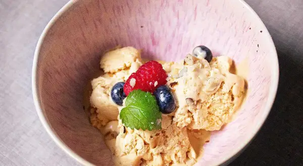 En skål med krämig dulce de leche glass, toppad med färska bär och mynta. En härlig dessert som smälter i munnen.