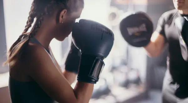 A boxer trains with her coach, practicing punches. This image shows the dedication needed to learn how to be a boxing coach.