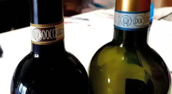 Dwie butelki włoskich win DOCG, czerwonego i białego, gotowe do degustacji.