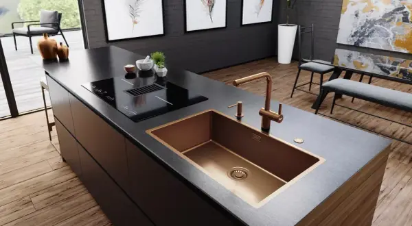 Cocina moderna con isla, placa de inducción y fregadero de cobre. Varios tipos de fregaderos, como este de diseño, realzan la estética.