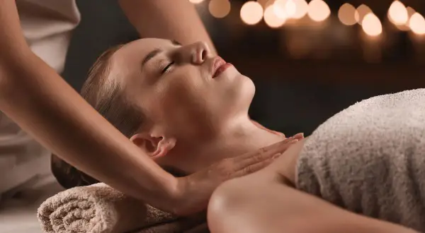 Relaksacyjny masaż karku i ramion w **day spa Szczecin**. Kobieta z zamkniętymi oczami odpręża się pod dotykiem masażystki.