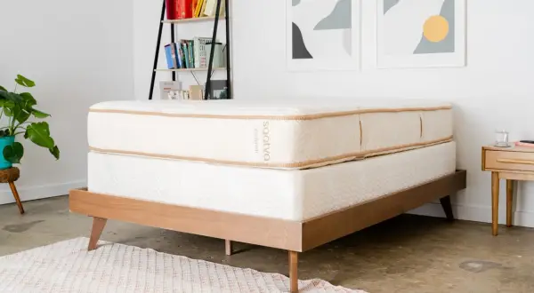 A Saatva mattress on a wooden bed frame, perfect for answering "cual es el mejor colchon para dolor de espalda.