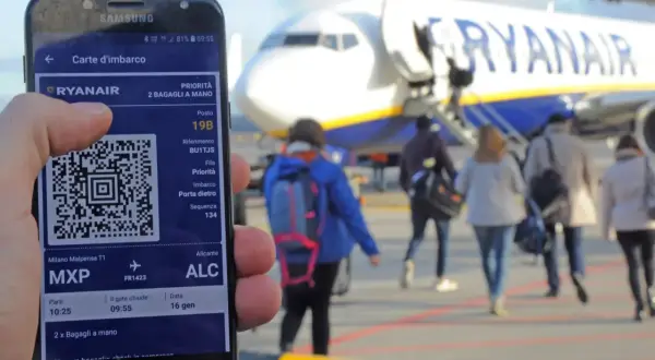 Telefon z kartą pokładową Ryanair, gotowy do podróży. W tle samolot i pasażerowie.