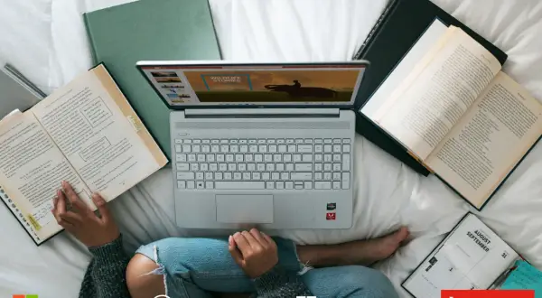 Osoba korzysta z laptopa z systemem Windows 10, otoczona książkami i notatnikiem.
