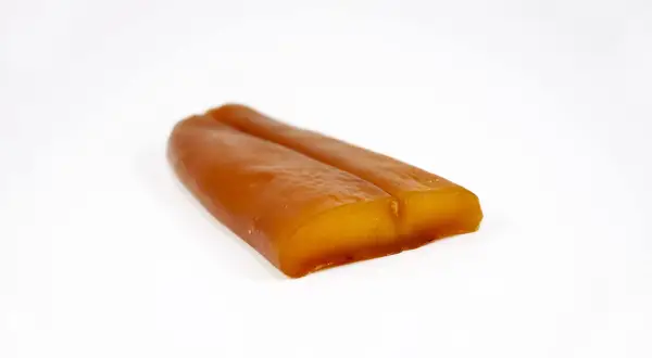Zwei goldbraune, längliche Stücke Bottarga di Muggine liegen nebeneinander auf weißem Grund.