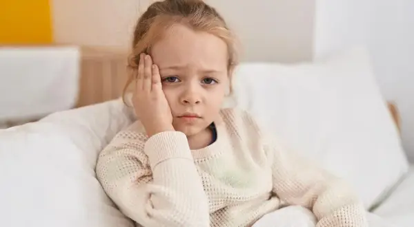 Ein trauriges Kind mit Kopfschmerzen, das sich im Bett ausruht. Vielleicht ist es ein Zeichen für schnelles Wachstum.