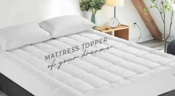 A plush mattress topper with two white pillows sits on a bed, promising a night of sweet dreams.