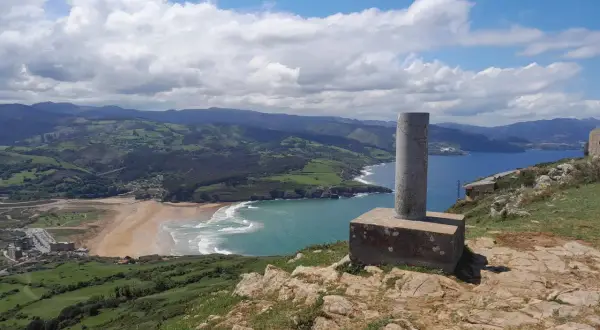 Vistas desde Punta Lucero: costa verde, playa dorada y mar azul bajo un cielo nublado.