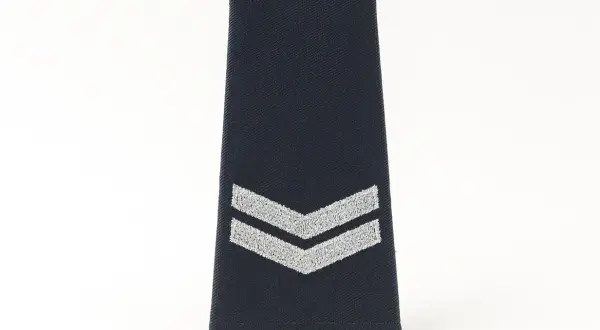 Granatowa naszywka z dwoma srebrnymi szewronami, symbolizująca stopnie w policji.