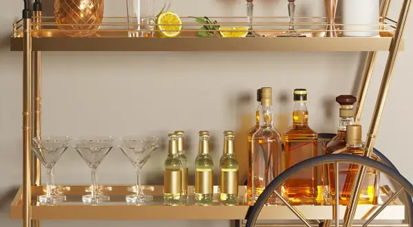 Elegancki barek w salonie z butelkami whisky, kieliszkami do martini i złotym dzbankiem w kształcie ananasa. Pomysły na stylowe przyjęcie.
