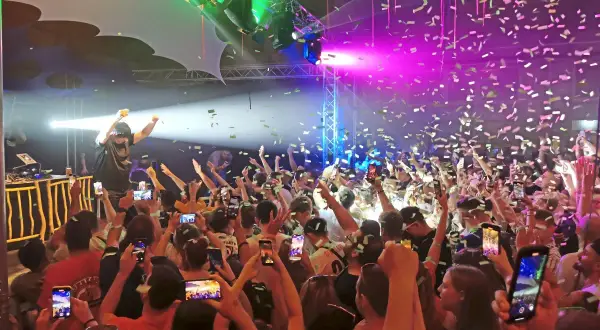 Konfetti regnet auf eine jubelnde Menge bei einem Konzert. Ein DJ steht auf der Bühne, während die Leute ihre Handys hochhalten, um den Moment beim Altdorfer Wasen festzuhalten.