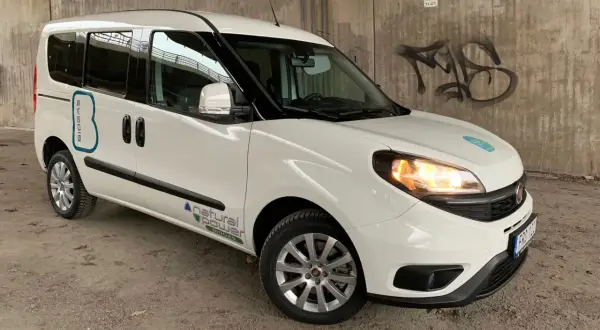 Vit Fiat Doblo med texten "BIOGAS" och "natural power" på sidan. En bil med ett potentiellt fiat doblo problem, kanske relaterat till dess biogasdrift.