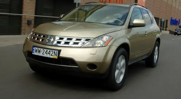 Złoty Nissan Murano 3.5 V6 w ruchu miejskim, z widoczną tablicą rejestracyjną WW 2442N.