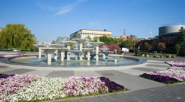 Fontanna w Gdyni, stare miasto, otoczona kolorowymi kwiatami i zielenią.