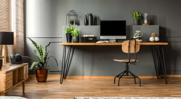 A modern desk setup with a computer, plants, and decorative items. This image shows how to hide cords on desk for a clean, organized workspace.