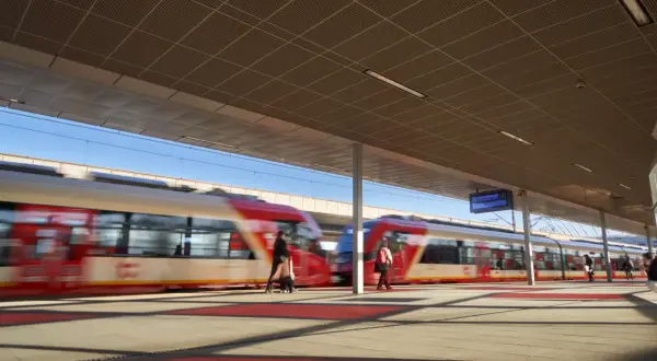 Pasażerowie kupują skm bilety warszawa na peronie, gdzie pociągi SKM w Warszawie szybko przejeżdżają.