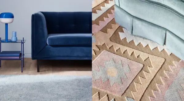 A dark blue sofa next to a light blue rug and a patterned rug with geometric designs.