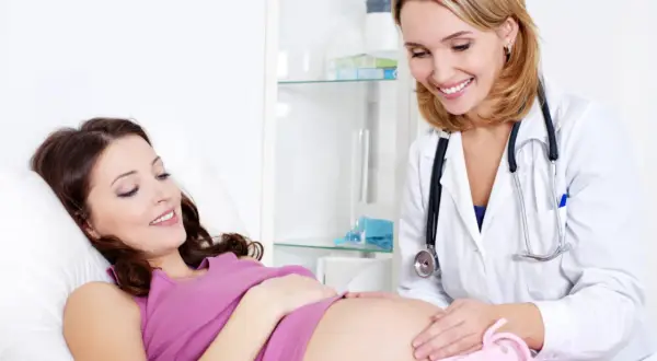 Uśmiechnięta lekarka bada brzuszek przyszłej mamy. To chwile radości dla każdej lactinova mama.