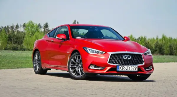Czerwony Infiniti Q60s na tle zieleni. Eleganckie coupe gotowe do jazdy.