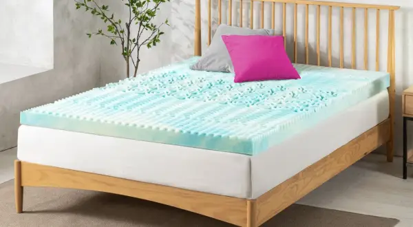 A blue and white memory foam mattress topper with a textured surface sits on a wooden bed frame. Perhaps this is why is my memory foam mattress so uncomfortable.