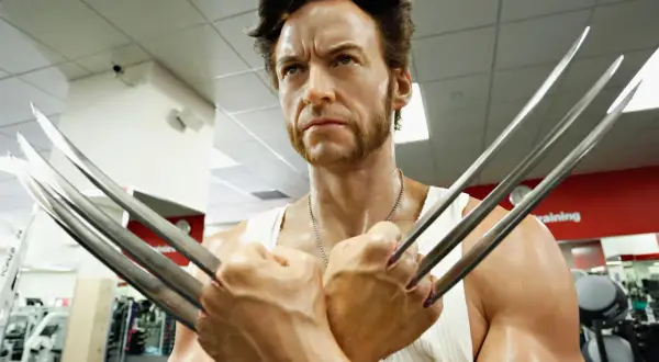 Wolverine, avec sa barbe distinctive et ses griffes rétractées, pose dans une salle de sport.