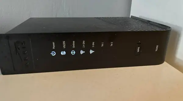 Czarny router Arris TG2492 z widocznym przyciskiem WPS i wskaźnikami statusu: Power, US/DS, Online, 2.4 GHz, 5 GHz, Tel 1, Tel 2.