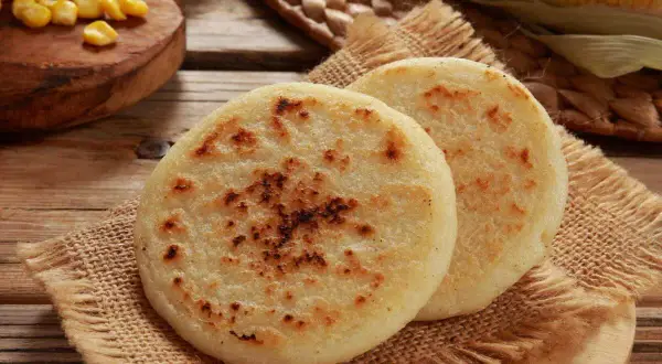 Deux arepas dorées, garnies de maïs, sur une toile de jute. Un délice à déguster !