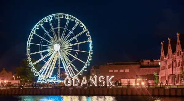 Nocne Gdańsk: diabelski młyn i wielki napis "GDAŃSK" to atrakcje dla dorosłych. Woda odbija światła miasta.
