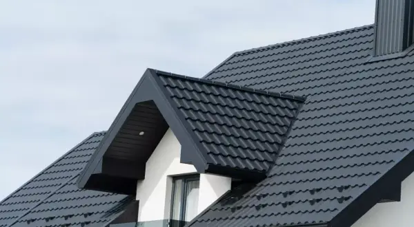 Nowoczesny, ciemnoszary dach dwuspadowy 200m2. Elegancka blachodachówka z widocznym kominem i okapem.