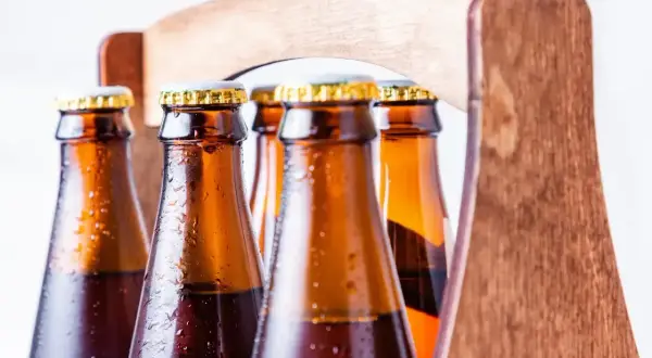 Zimne butelki piwa w drewnianym trayu. Z czego robi się piwo? Z chmielu, słodu i wody, a potem fermentuje.
