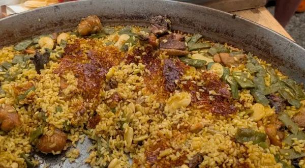 Paella de carne recién hecha, con arroz dorado, trozos de carne tierna, judías verdes y un delicioso socarrat crujiente.