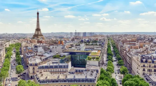 Vy över Paris med Eiffeltornet i fjärran. En grönskande allé leder mot stadens centrum, där takåsarna vittnar om stadens rika historia och många museum.
