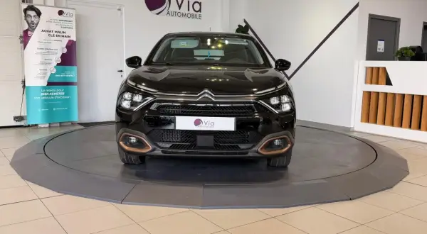 Une voiture noire sur un plateau tournant, prête pour un dépôt vente véhicule. Le logo Via Automobile est visible.