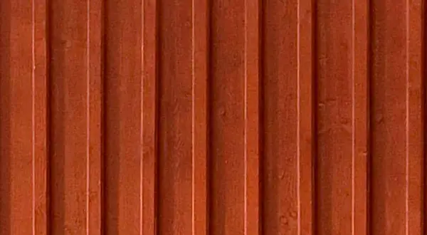En närbild av en rödbrun, gammaldags lockpanel. Träets ådring syns svagt under färgen.