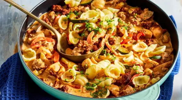 Hackfleisch-Nudel-Pfanne mit Zucchini und Paprika in cremiger Sauce, garniert mit Schnittlauch.