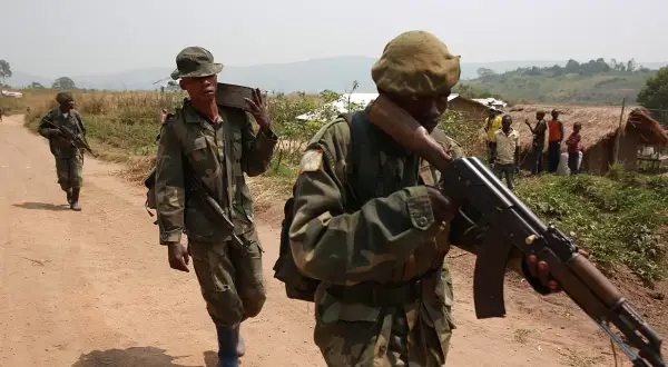 Soldater i Kongo under en tid av konflikt, bär vapen och utrustning längs en dammig väg.