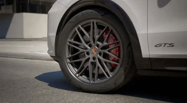 Zbliżenie na koło Porsche Cayenne GTS z czerwonymi zaciskami hamulcowymi i felgą w ciemnym kolorze.