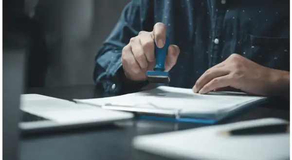 Main tenant appose un tampon sur un document. Le droit fixe d'enregistrement est de 125 €.