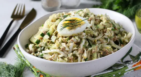 Lekka sałatka z tuńczykiem, jajkiem i ogórkiem, udekorowana koperkiem. Idealna na szybki lunch.