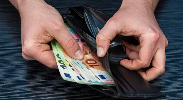 Ręce wkładają euro do portfela. Może to zarobki lakiernika w Niemczech.