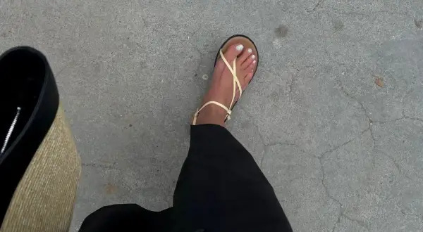 En fot i ljusgula sandaler från Vero Moda skor, med svart kjol och en stråväska.