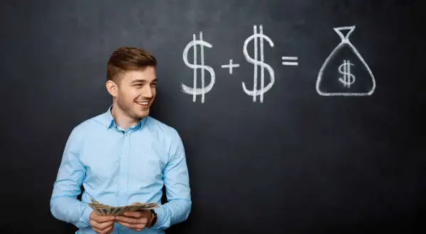 Giovane uomo con soldi in mano, davanti a una lavagna con disegnati simboli del dollaro e un sacco di soldi. Calcola quanto costa un dipendente che prende 1.500 euro.